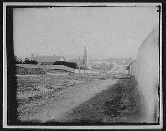 Looking down dirt street toward waterfront of Dunedin, Dunedin, New Zealand, 1895