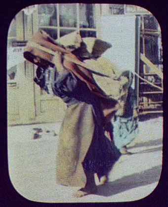 Woman with heavy load strapped to her back, India, 1895