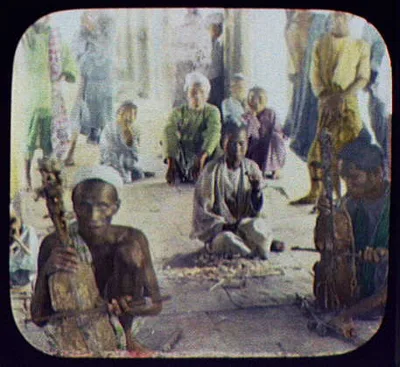 Men squatting on sidewalk  - two playing stringed instruments in…, India, 1895