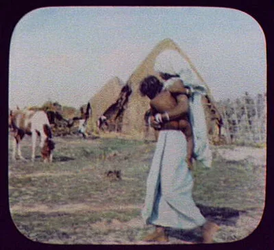 Woman with baby and pony in front of thatched houses, India, 1895