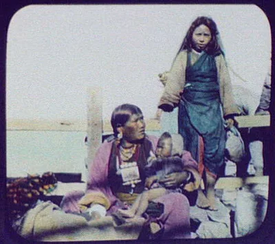 Mother sitting, holding baby; young girl standing, Java, Indonesia, 1895
