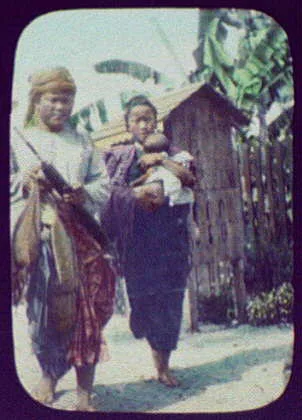 Man, woman, and child in front of small hut on stilts, Thailand, 1895