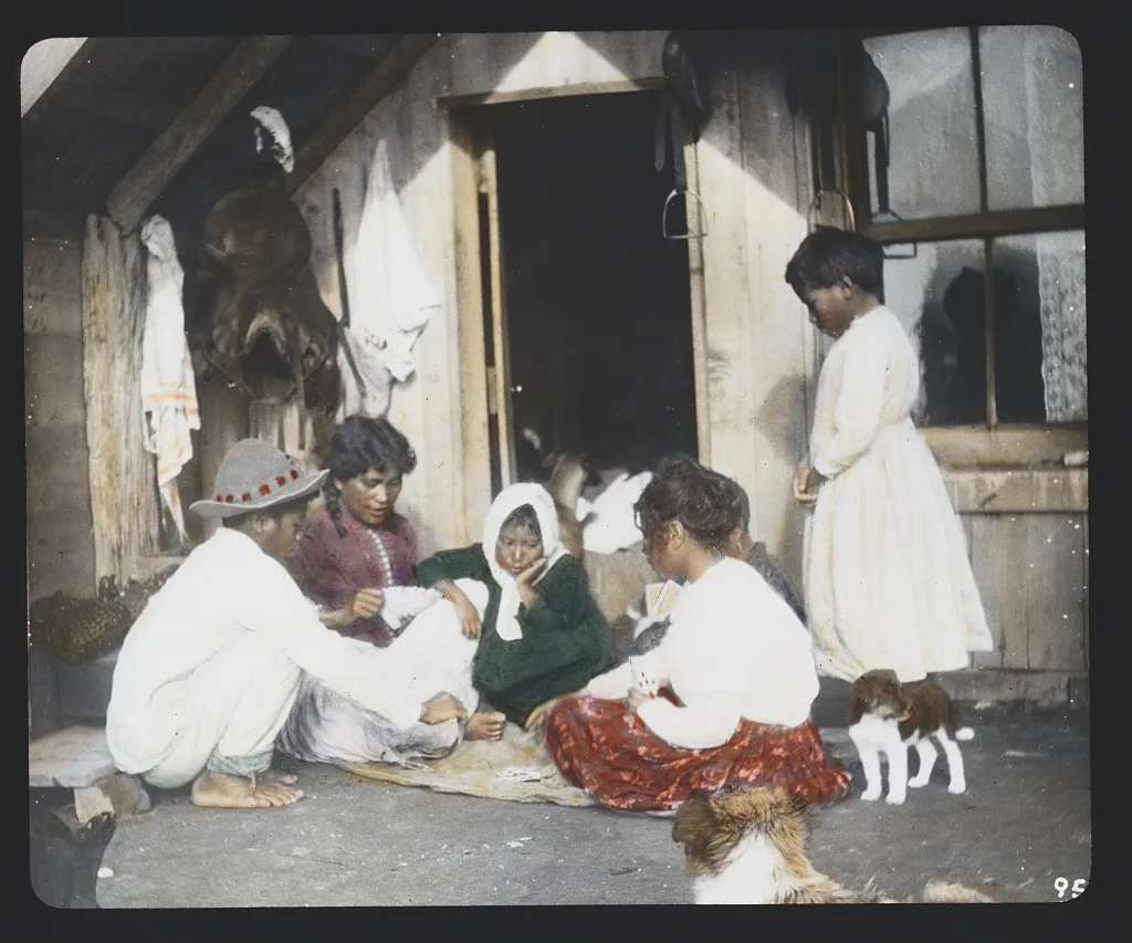 Maori woman and children playing cards on doorstep of home -…, New Zealand, 1895