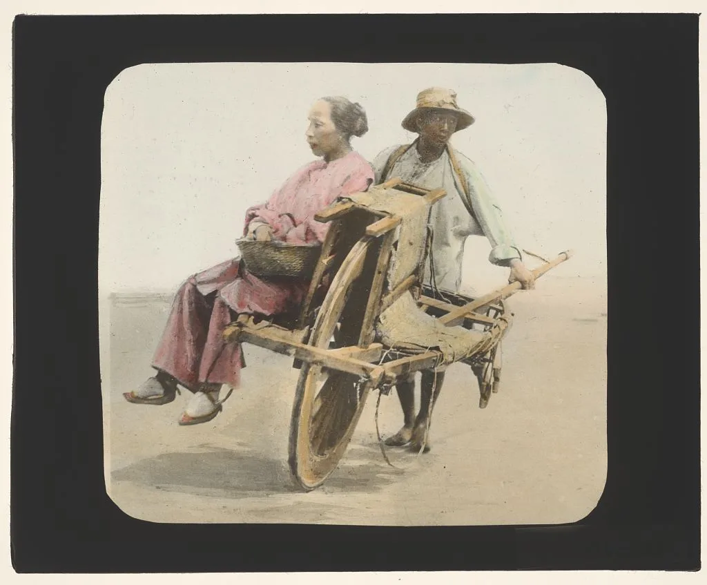 Woman seated in wheelbarrow pushed by men, China, 1895