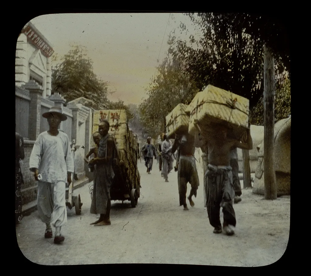 Coolies carrying boxes of tea beside Globe Hotel, China, 1895
