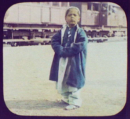 Girl standing; railway train in background, China, 1895