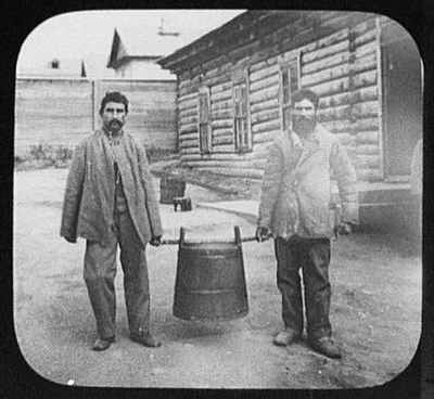 Two convicts carrying large pot of soup, Siberia, 1895