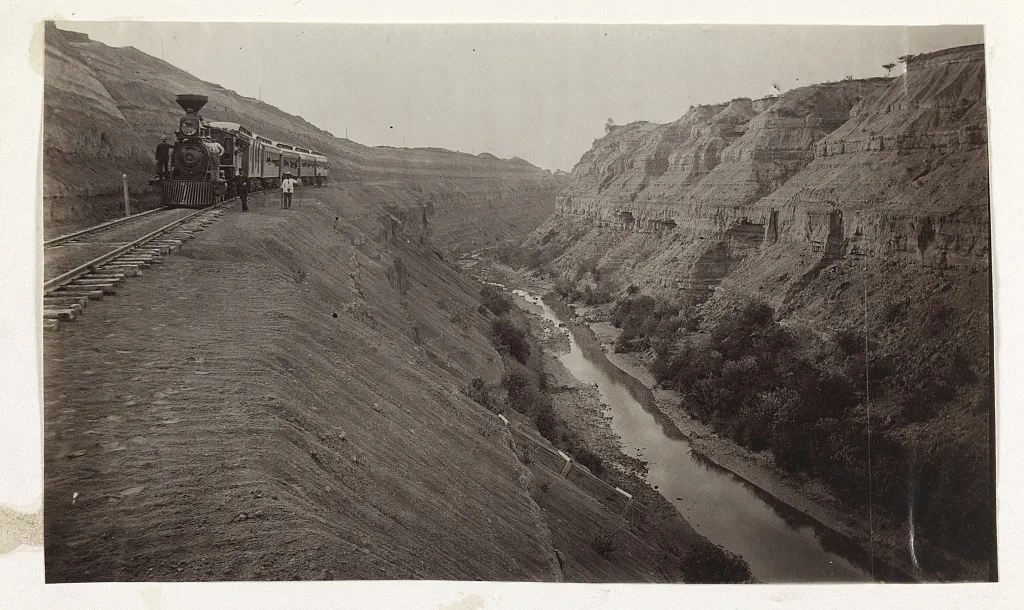 [People inside and outside stopped train alongside a canyon in Mexico], 1883